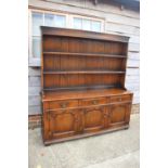 An oak dresser with plate shelves over three drawers and three cupboards enclosed ogee panelled