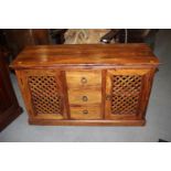 An Indonesian hardwood sideboard, fitted three drawers flanked lattice cupboards, on block base