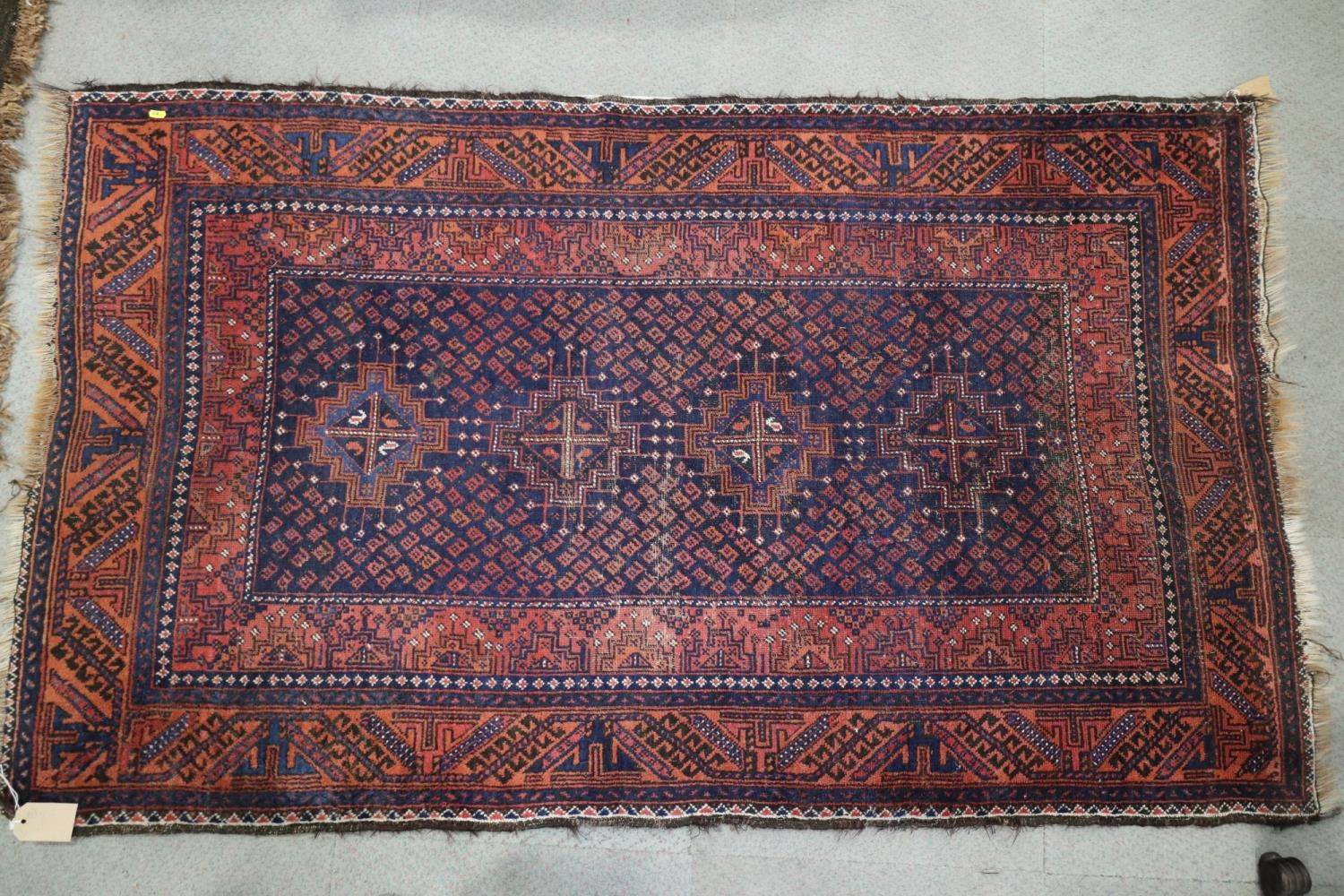 A Bokhara type rug with four stepped medallions on a blue ground with geometric borders in shades of
