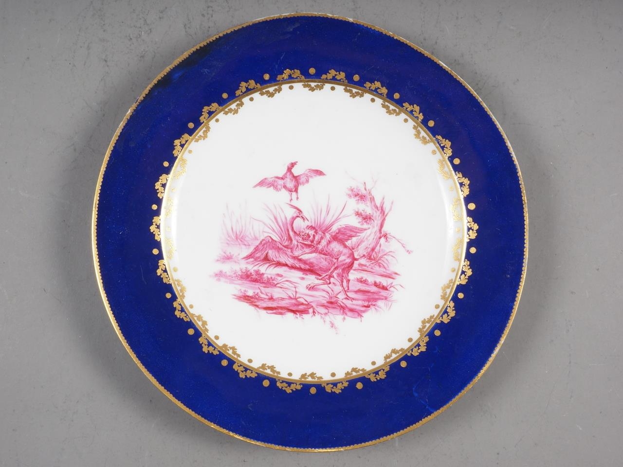 A Sevres style cabinet plate, decorated central puce animals in a landscape with blue and gilt