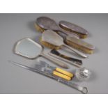 An engine turned silver dressing table set, two other brushes, a silver plated game skewer, etc