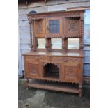 A Victorian carved oak sideboard, the upper section fitted shaped cupboard enclosed glazed panel