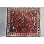 A Persian tribal mat with stepped diamond medallion on a red ground, 34 1/2" x 30" approx, and a