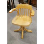 A light hardwood swivel lath back desk chair, on splay supports