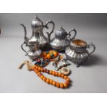 A silver plated four-piece teaset, an amber necklace and another similar