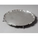An early 20th century pie-crust edge silver salver, on three pad supports, 10" dia, 20.3oz troy