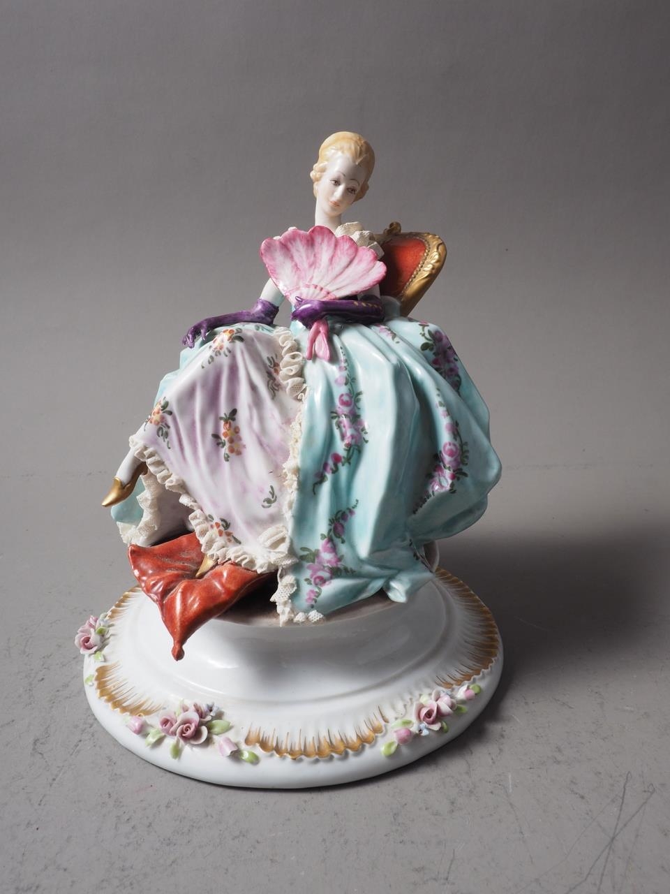 A Capodimonte figure of a seated woman with a fan, 7 3/4" high (restorations)