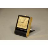 A Jaeger travelling alarm clock with Arabic numerals and gilt dial, 3 1/4" high