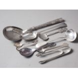 A white metal serving spoon, a Georgian silver tablespoon, a silver ladle, two pairs of silver sugar
