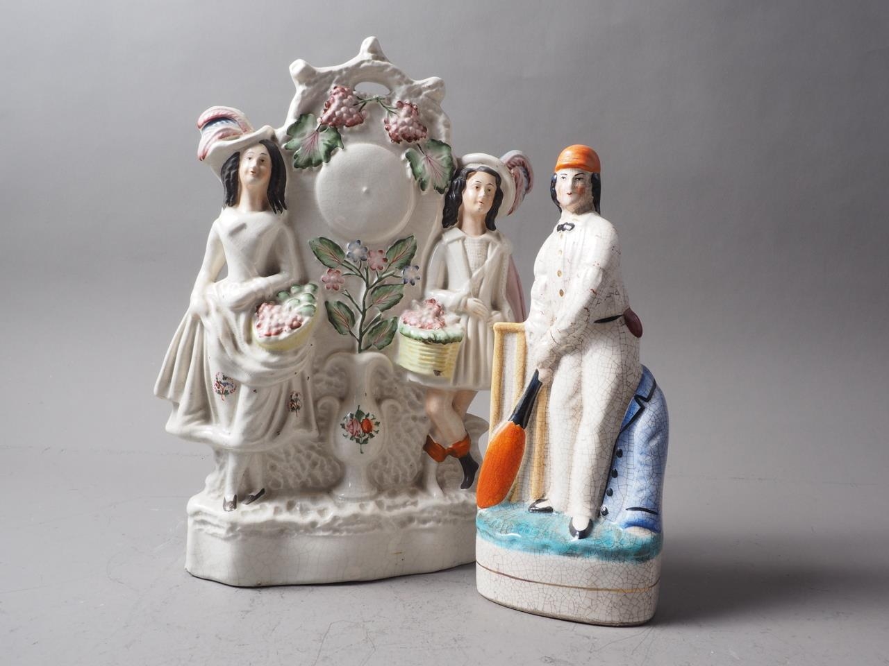 A 19th century Staffordshire watch group, "gardeners" 13" high, and a similar cricketer, 10" high