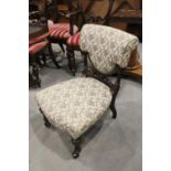 A Victorian carved walnut low seat salon chair with stuffed over seat and padded back, on later