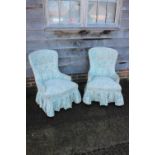 A pair of low seat nursing chairs, button upholstered in a blue floral fabric, on square supports