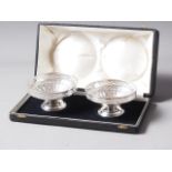A pair of white metal bonbon dishes with pierced and fluted decoration, on stepped bases, in case,
