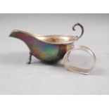 A silver sauce boat with scroll handle and three paw supports, and a silver napkin ring, 3.0oz