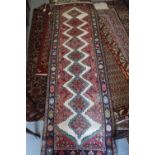 A Kazak style rug with nine star diamond lozenges on a cream ground with pink edges and blue