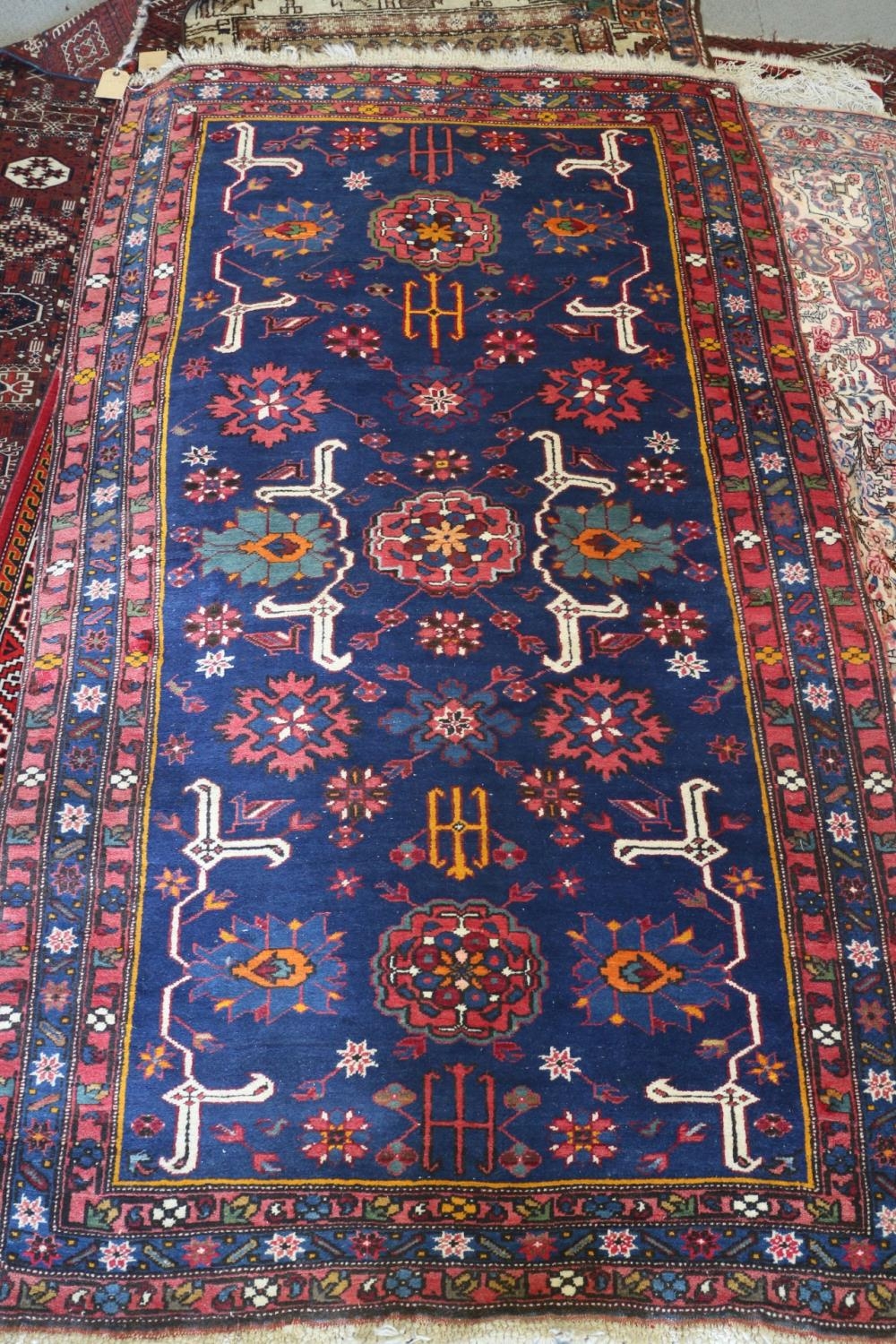 A Kuba rug with three medallions, candelabra and stylised birds on a dark blue ground and triple-