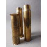 A brass trench art shell case with engraved decoration, 9 1/4" high, and two others, 12" high