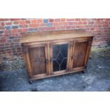 An oak display cabinet enclosed leaded glazed door and two panelled door, on bun feet, 46" wide x 16