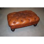 A Tetrad button upholstered leather topped stool, on turned supports, 38" wide x 28" deep x 16" high