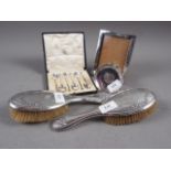 A set of six silver teaspoons, two silver backed brushes, a silver photo frame and a silver dish,
