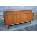 A 1950s G Plan Librenza teak sideboard, fitted three drawers over two bi-fold doors, on ebonised