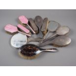 A pink enamelled four-piece dressing table set (damages), five silver mounted brushes and a