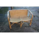 A rattan two-seat settee with shaped seat rails, 42" wide x 29" high
