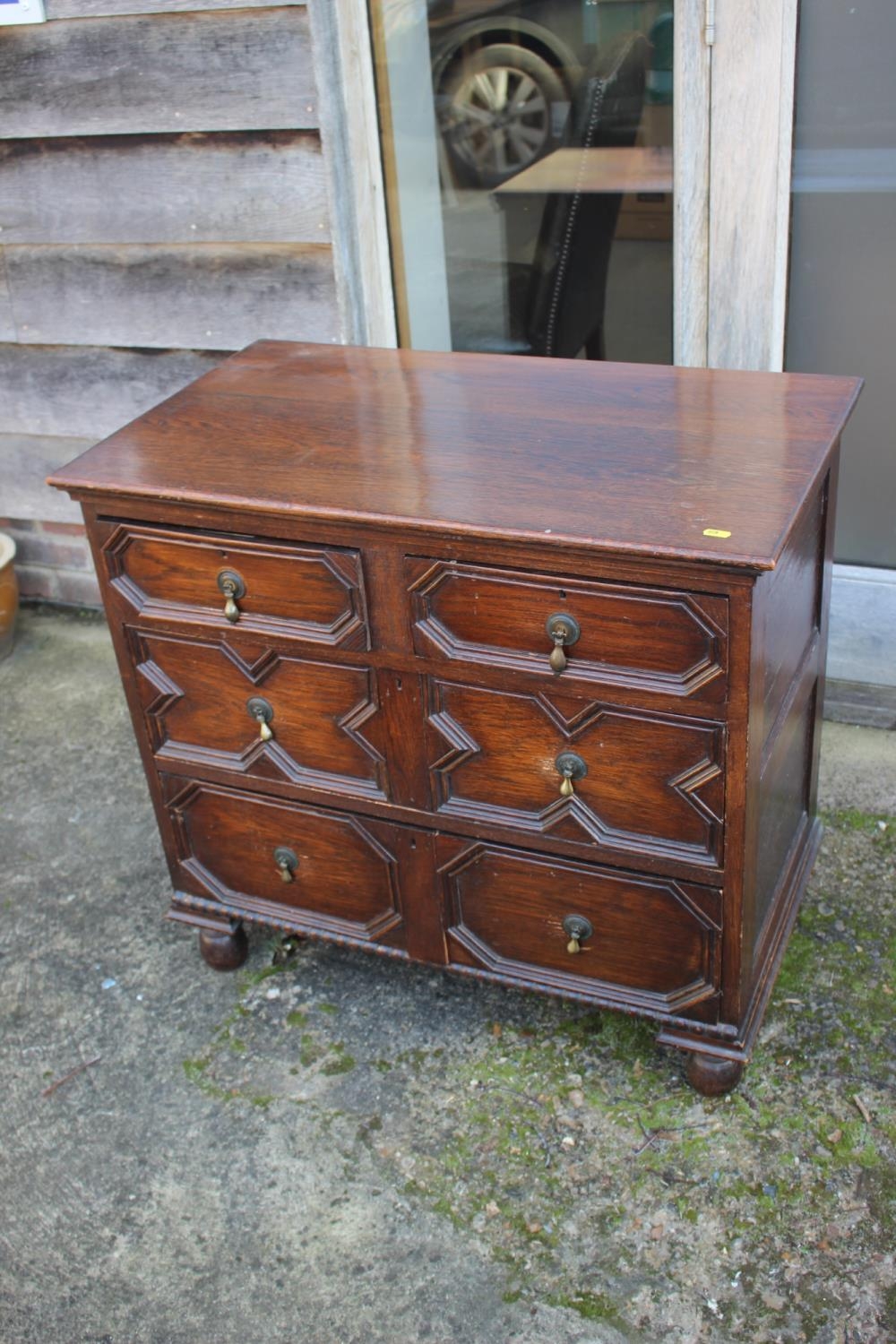 An oak chest of two short and two long drawers of 17th century design with fielded panel fronts,