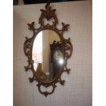 An oval wall mirror, in Rococo style scrolled gilt frame, mirror plate 25" x 15"