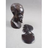 A carved ebony head of a man, 9" high, a shallow relief bust of a woman, 10 1/4" high, and a post-