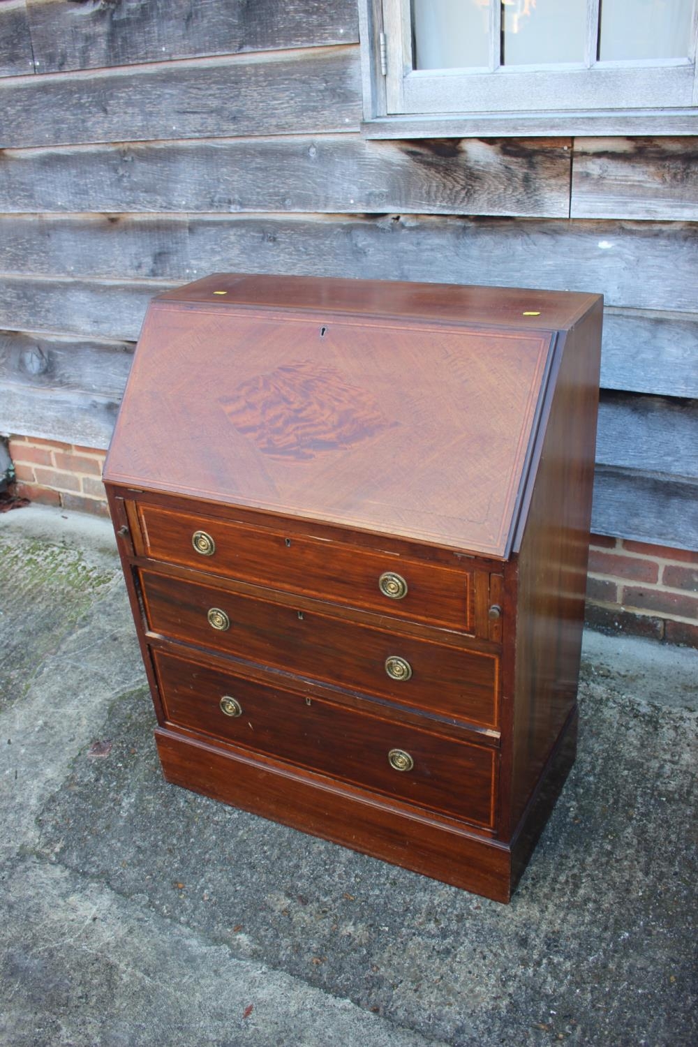 An Edwardian mahogany and satinwood banded fall front bureau with fitted interior over three long