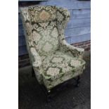 A 17th century style wing armchair, upholstered in a green brocade
