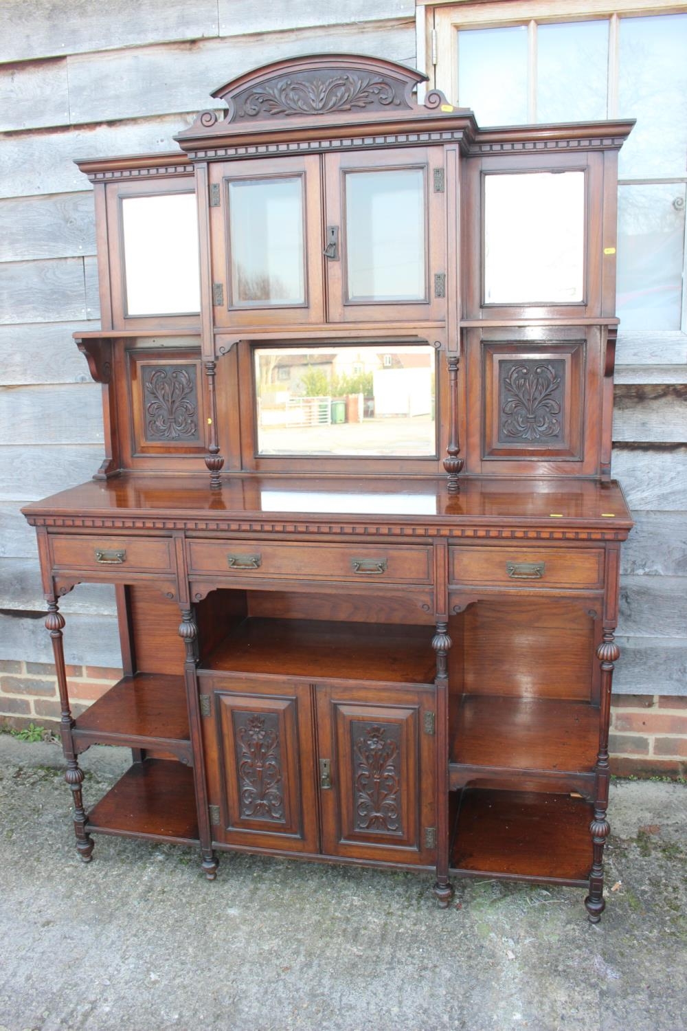 An Edwardian walnut dresser, the upper section fitted three mirror panels and glazed cupboard,