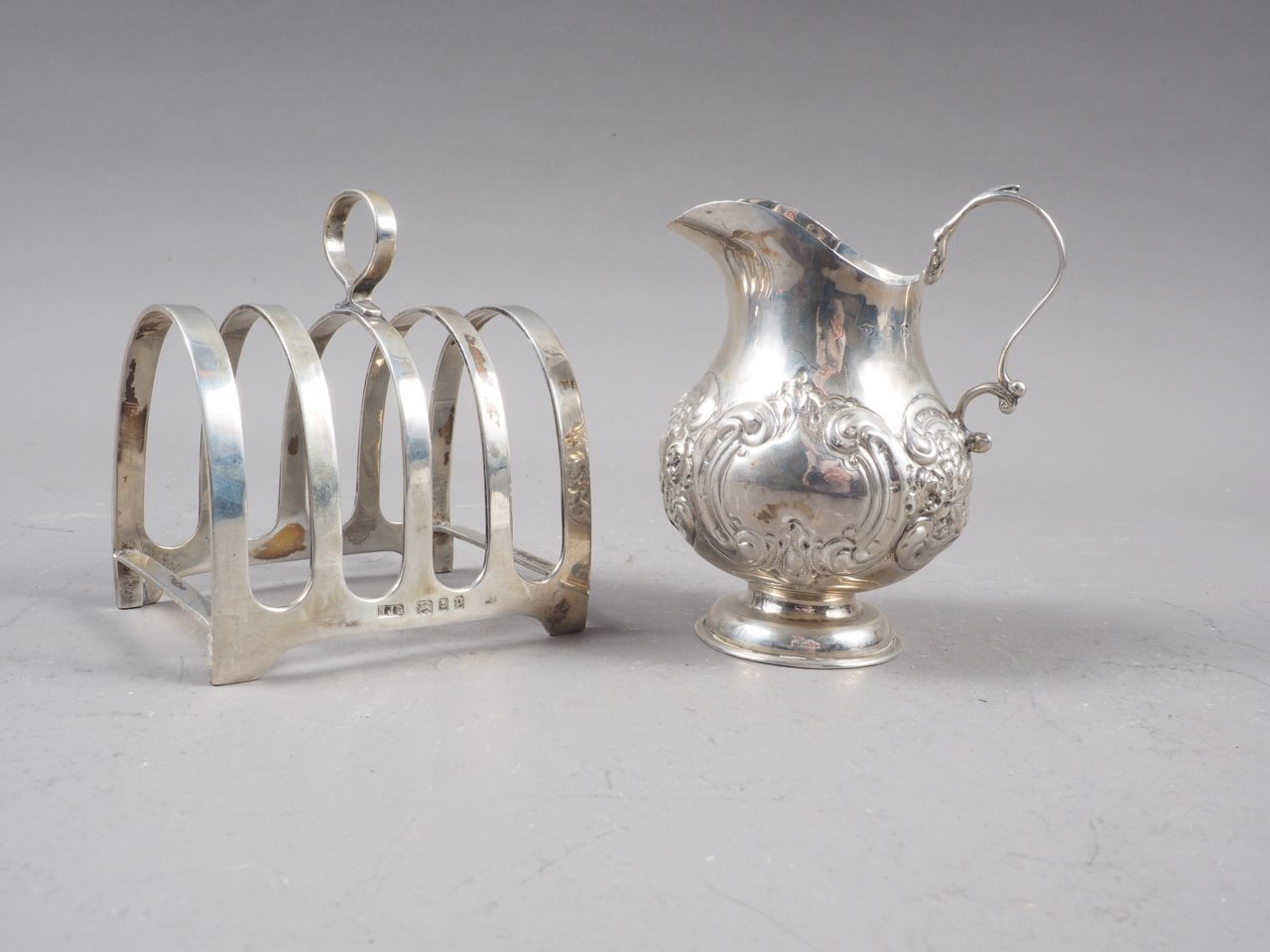 An embossed silver cream jug, 2oz troy approx, and a silver toast rack, 3.9oz troy approx