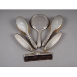 A silver backed dressing table set, comprising four brushes, a comb and a hand mirror
