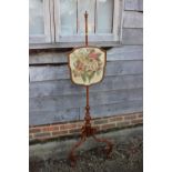 A late Victorian pole screen with embroidered panel, on scroll supports