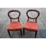 A pair of mahogany dining chairs in a corded rust fabric, on turned, reeded tulip supports