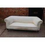 An early 20th century chesterfield type settee, upholstered in a cotton ticking, on turned supports