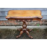 A 19th century rosewood serpentine fold-over top card table, on turned column and quadruple scroll