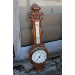 A light oak cased barometer and thermometer with carved decoration, 34 1/2" high