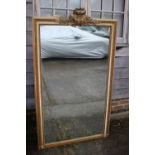 An Edwardian carved and giltwood rectangular framed wall mirror with scroll and laurel leaf crest,