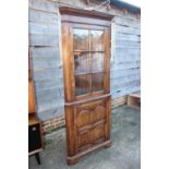 An oak corner display cabinet, the upper section enclosed lattice glazed door over ogee arch
