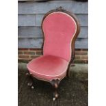 A carved mahogany spoon back nursing chair, upholstered in a pink fabric, on cabriole castored