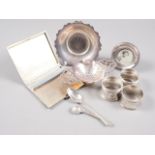 A silver cigarette case with engine turned decoration, a silver tea strainer, a pair of silver