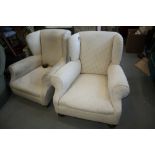 A pair of deep seated wing armchairs, covered in a white figured brocade, on bun feet (one bun