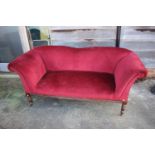 A late Victorian mahogany framed scroll arm two-seat settee, upholstered in a red velour, on
