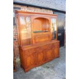 A yew wall unit, the upper section fitted cocktail compartment, flanked by glazed doors over three