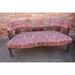 An early 20th century rosewood and line inlaid "conversation" settee with splat and spindle padded