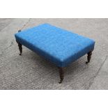 A stool, upholstered in a blue fabric, on turned and brass castored supports, 39" wide x 26" deep