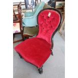 A spoon back nursing chair, button upholstered in a red velour, on turned and castored supports